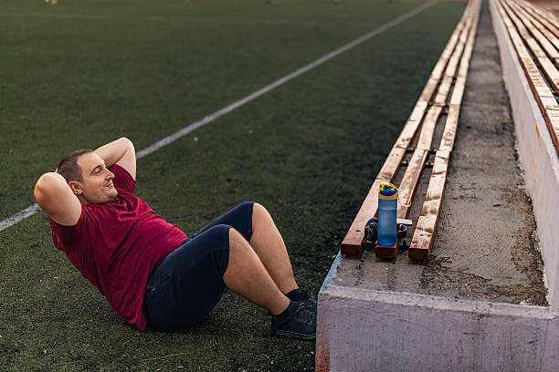 istock Overweight man doing abdominal exercise on the sport field. 2243035731