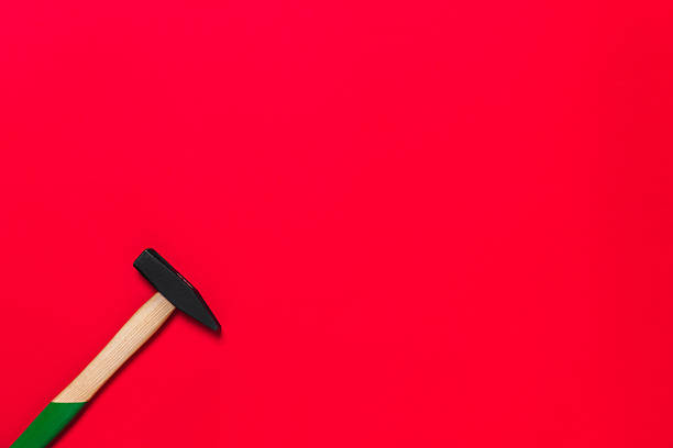 Hammer is isolated on a red background with place for text. Shop banner with construction tools. New Year or Christmas festive backdrop. One of the basic home use instrument for hammering nails.