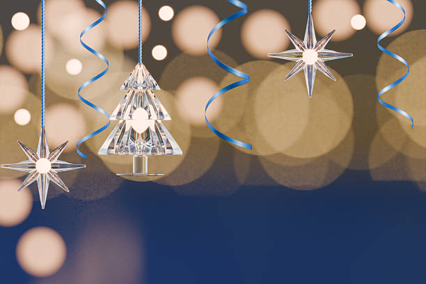 Crystal Christmas stars and tree ornaments hang with blue ribbons in front of warm bokeh lights. 3d rendering