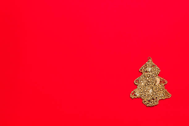 istock Christmas tree made with golden color material on red background with copy space for text, horizontal. Rich new year toy decorated with glitter bubbles 2243040507