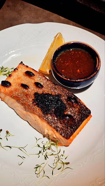 istock Salmon fillet with lemon and sauce on a white plate 2243040753