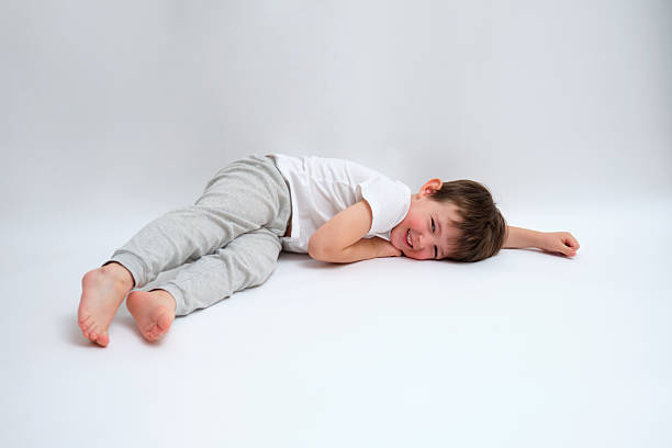 Teenage boy smiling and lying head down on white background