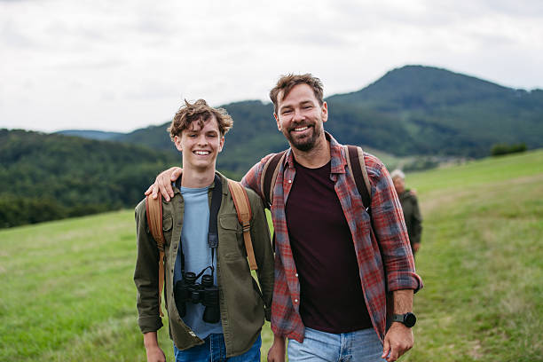 Father spending weekend with teen son on hike in nature.