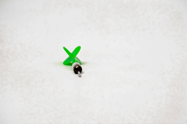 A close-up shot of a single green dart on a white background, showcasing the precision needed
