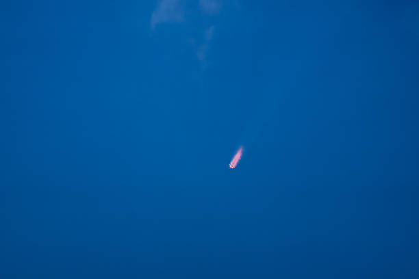 Cape Canaveral, FL, USA – October 19, 2025: Minimalist horizontal frame of the SpaceX Falcon 9 Starlink launch from SLC-40, showing a pink-tinged exhaust streak as the rocket ascends through the atmosphere against a deep blue sky.