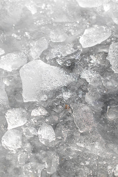 istock Close-up abstract texture of broken, melting ice pieces. Sunlight shines through the semi-transparent fragments, showcasing the intricate details of frozen water during the spring thaw. 2243055871