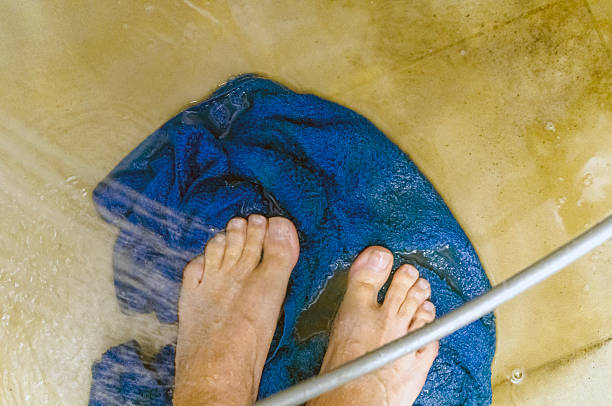 male bare feet standing on a dirty tiled floor of a bath, no people