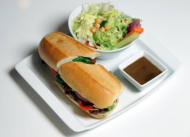 Sandwich with chicken and greens on a white plate and a white background