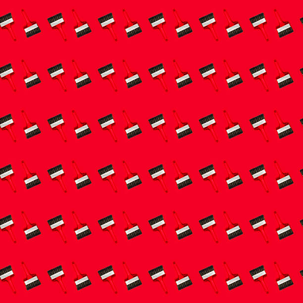 Seamless pattern with large wide new red brush for construction or wall painting or canvas priming on a red background. Christmas wallpaper. Textured banner for a hardware store or art shop. Close-up.