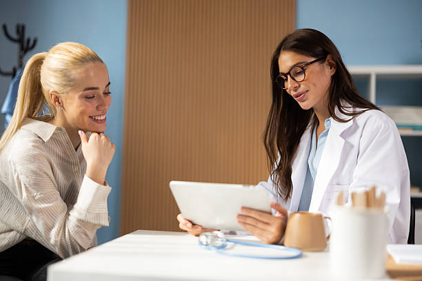 Female doctor and patient having a consultation, reviewing health information on a tablet