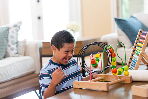 istock Joyful child with Down syndrome enthusiastically plays with an educational toy on a table. 2243086891