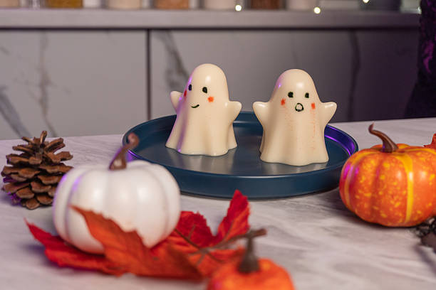 Cute halloween ghost jellies on blue plate with pumpkins and autumn leaves