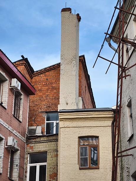 A tall white brick chimney between two weathered