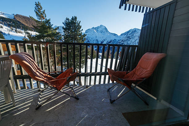 istock Two folding chairs on snowy balcony with Alpine mountain view 2243102435