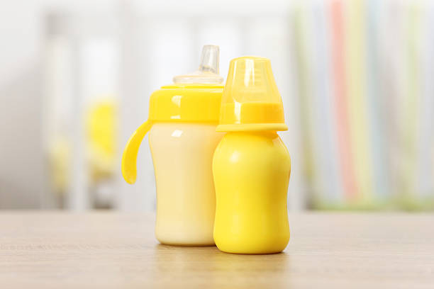 Feeding bottles with milk on wooden table indoors
