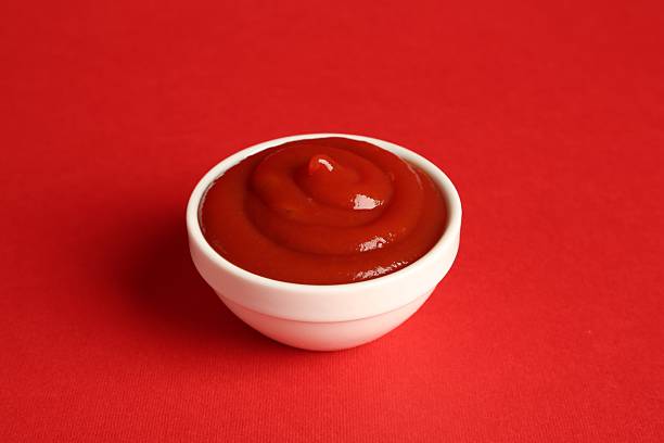 Ketchup leaked out of the package, creating a stain on a white background.