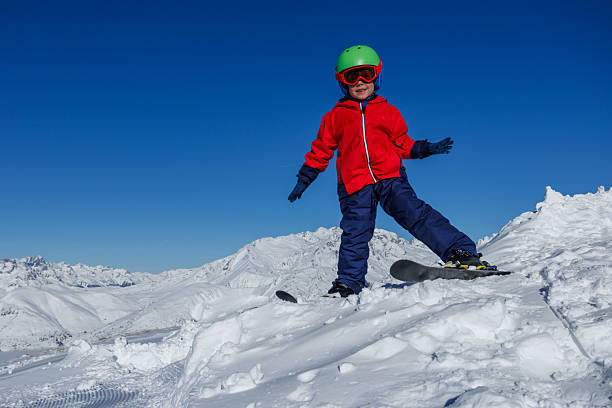 Caucasian girl 6 years old stands on top of snowdrift and waves her hand, greeting. Ruka ski resort.