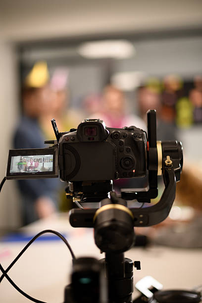 istock Camera on a tripod capturing an event with blurred people in the background at a festive setting during a celebration 2243112229