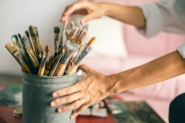 istock Artist hands selecting paintbrushes from a jar in a bright creative studio environment 2243115851
