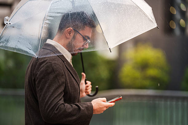 istock Man using smartphone under umbrella in the rain 2243130374