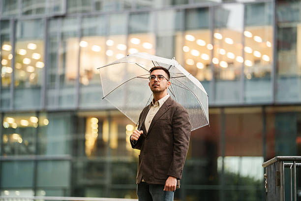 istock Man standing outdoors with umbrella in front of office building 2243130397