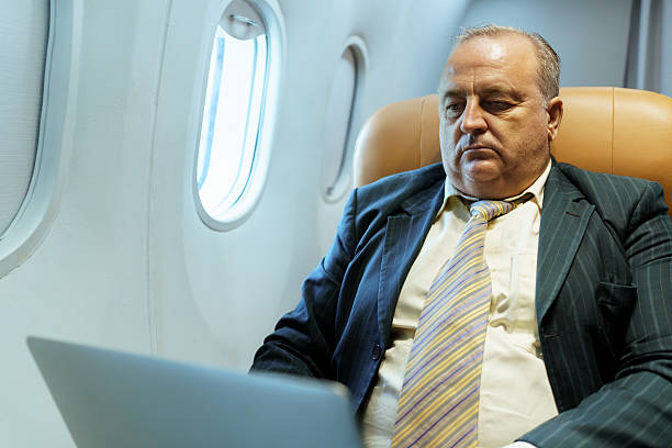 istock Businessman working on laptop in airplane business class during flight 2243141708