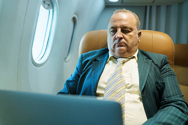 istock Businessman working on laptop in airplane business class during flight 2243141711