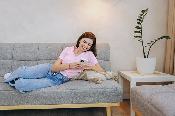 istock Young Woman Relaxing on Sofa Using Smartphone at Home 2243169589
