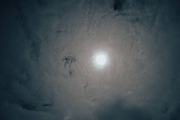 Full moon astral sky with milky clouds. Dramatic clouds in mystic moonlight. Moon illuminating a dark, cloudy night sky