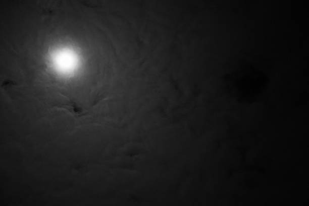 Full moon astral sky with milky clouds. Dramatic clouds in mystic moonlight. Moon illuminating a dark, cloudy night sky