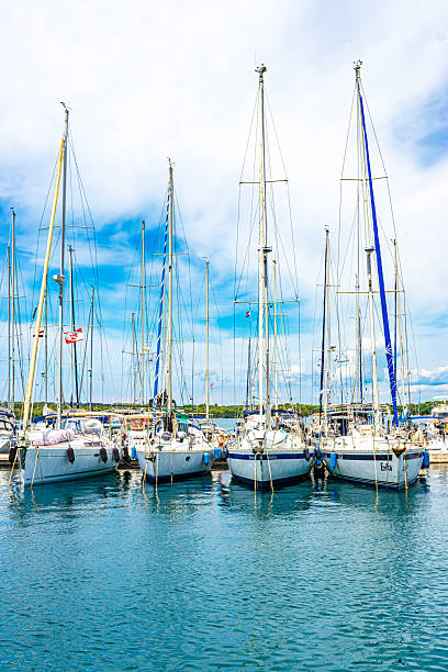 istock Four white yachts in a sunny harbour among sea water 2243173741
