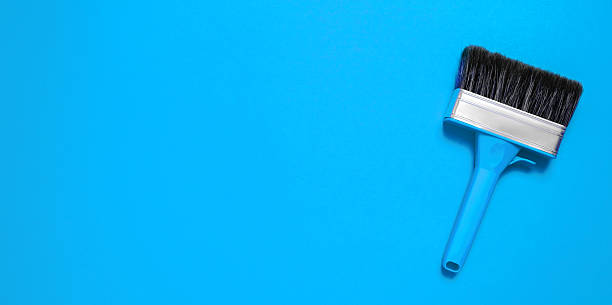 istock Large new brush in metal edging with plastic handle for construction painting or canvas priming on a blue background. Banner with copy space for a hardware store or art shop. Close-up. Clean bristle 2243174635