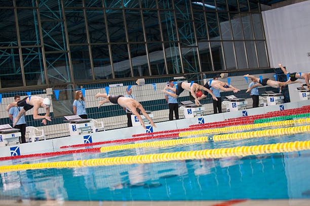 Freestyle stroke swimming competition start for men at a swimming tournament. Referees at the side of a swimming pool.