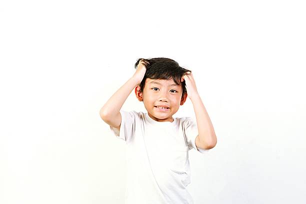 A cheerful little boy in a white shirt posing joyfully against a plain white background, expressing happiness and innocence in a minimalist studio portrait.