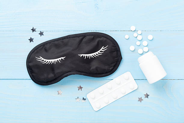 istock Sleeping mask with pills on wooden background, top view 2243178735