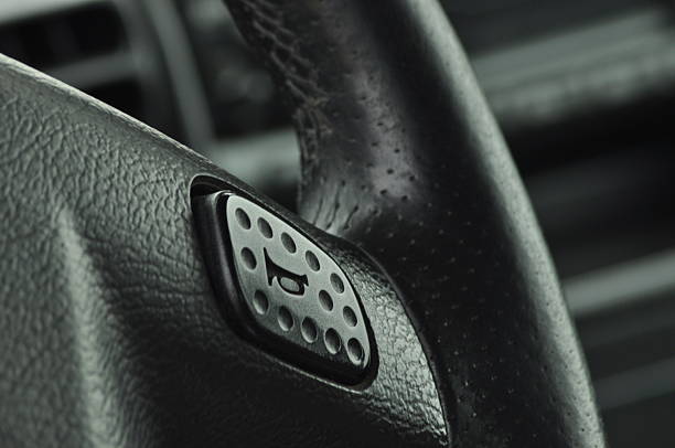 A close view of a car steering wheel highlighting the textured surface and a button. The image captures the details of everyday driving equipment in a vehicle cabin.