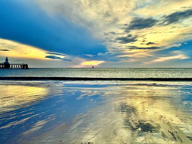 istock Dramatic cloudscape reflecting on wet sand with a pier and lighthouse at Blyth in Northumberland 2243181353