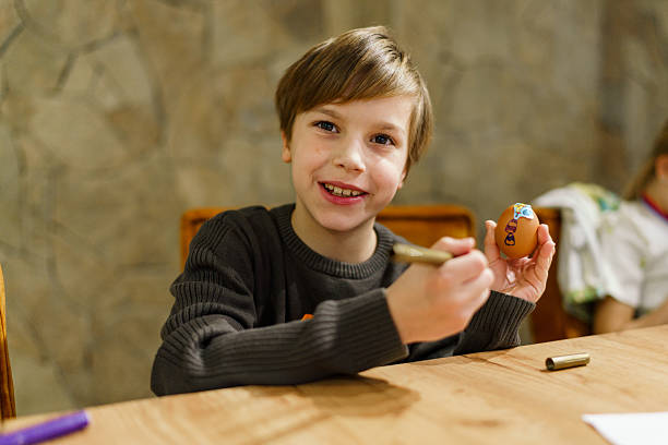 Smiling boy drawing on an easter egg, celebrating holiday tradition.