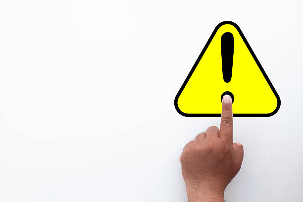 istock Warning Alert: Hand Pointing to Yellow Hazard Triangle Sign. 2243191938