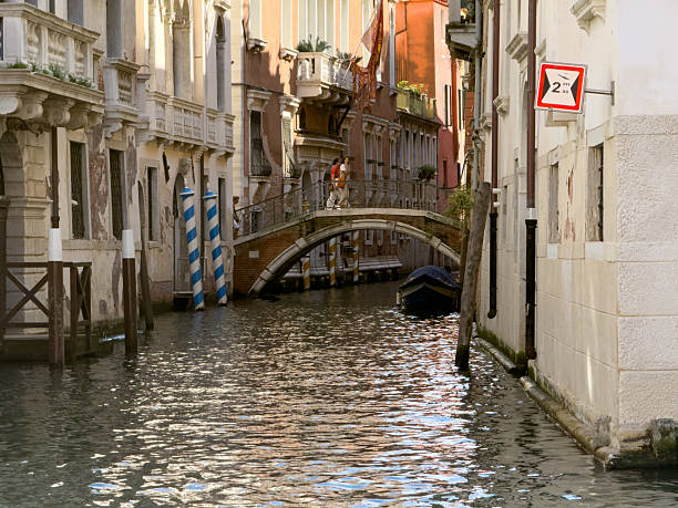 Picturesque view of the Grand Canal in Venice with traditional gondolas and colorful historic buildings under a clear blue sky. The scene captures the unique charm and architectural beauty of this iconic Italian city, with sunlight reflecting on the shimmering water.