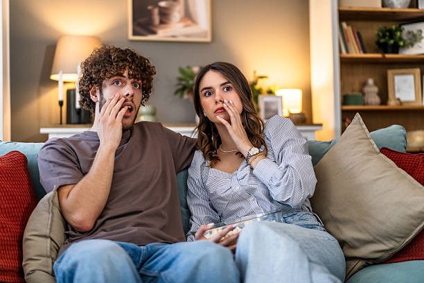 istock Young couple feeling scared watching horror movie at home 2243202148
