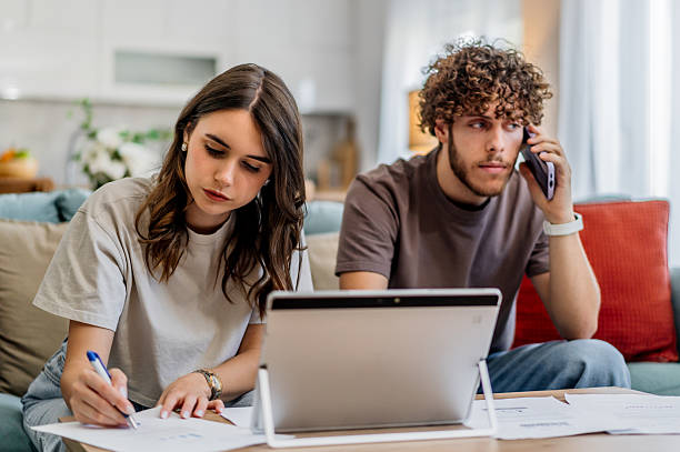 istock Young couple managing home finances and talking on phone 2243202235