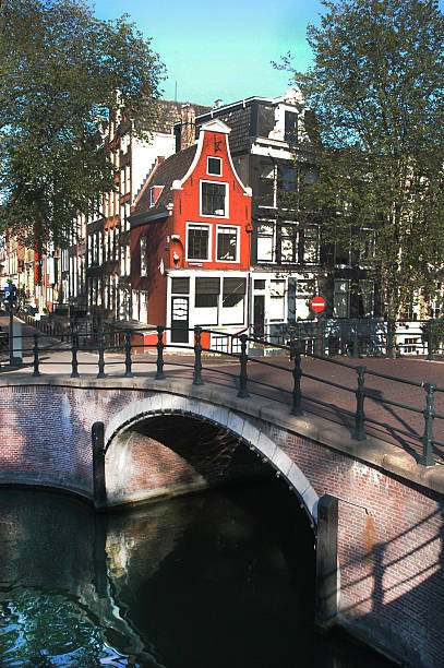 Canal Side Properties and Bridge, Amsterdam. Amsterdam is the Netherlands’ capital, known for its artistic heritage, elaborate canal system and narrow houses with gabled facades, legacies of the city’s 17th-century Golden Age.  Its Museum District houses the Van Gogh Museum, works by Rembrandt and Vermeer at the Rijksmuseum, and modern art at the Stedelijk.