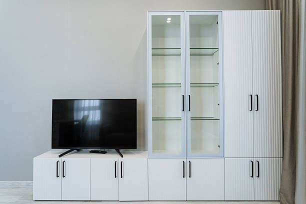 The elegantly designed living room features sleek white cabinets and a contemporary wallmounted flat screen TV, creating a stylish atmosphere perfect for relaxation and entertainment