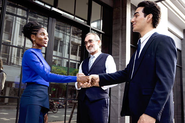 istock Happy businessman has handshake for greeting with business partner outside office. Successful African female officer shaking hands after finish deal outdoor. Cheerful business team shaking hands 2243228421