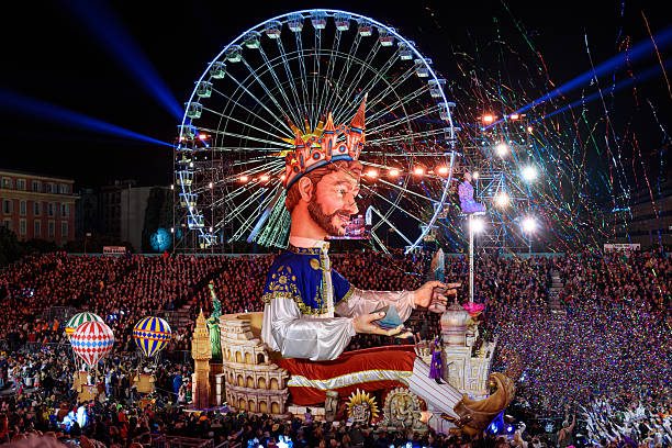 Nice, France - February 21, 2023: floats by night (the King) at the 150th annual Carnival parade of lights in Nice, Place Masséna, on the French Riviera. Ferris wheel in the background.