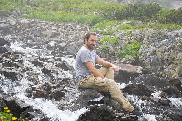 istock Man sitting on a rock on top of a mountain 2243231168