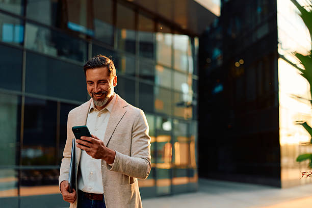 istock Happy businessman smiling using mobile phone in city 2243236753