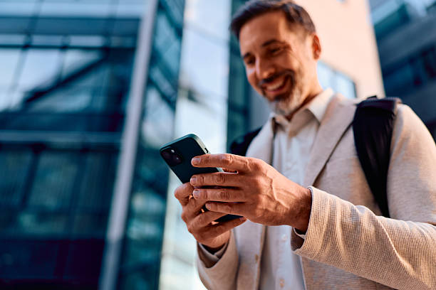 istock Mature adult man smiling while using smartphone outdoors 2243236942