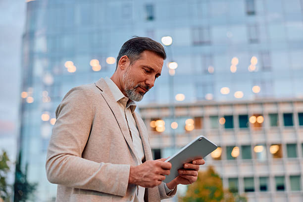 istock Mature businessman checking tablet in front of modern building 2243236995